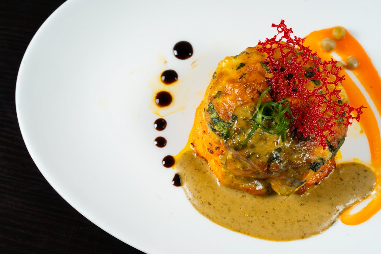 A gourmet dish presented with colorful sauce and artistic garnish on a white plate.