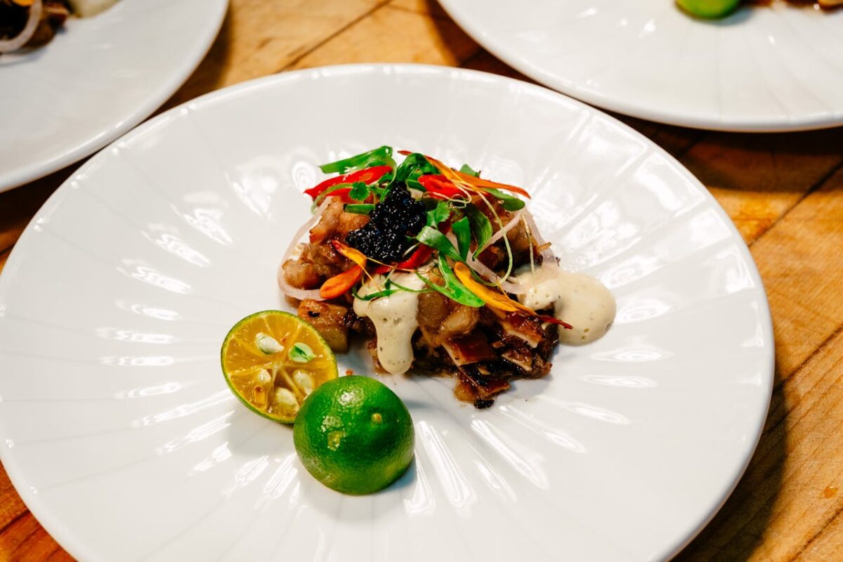 pexels photo 32754807 Delicious gourmet sisig with vibrant garnish and calamansi on a white plate.