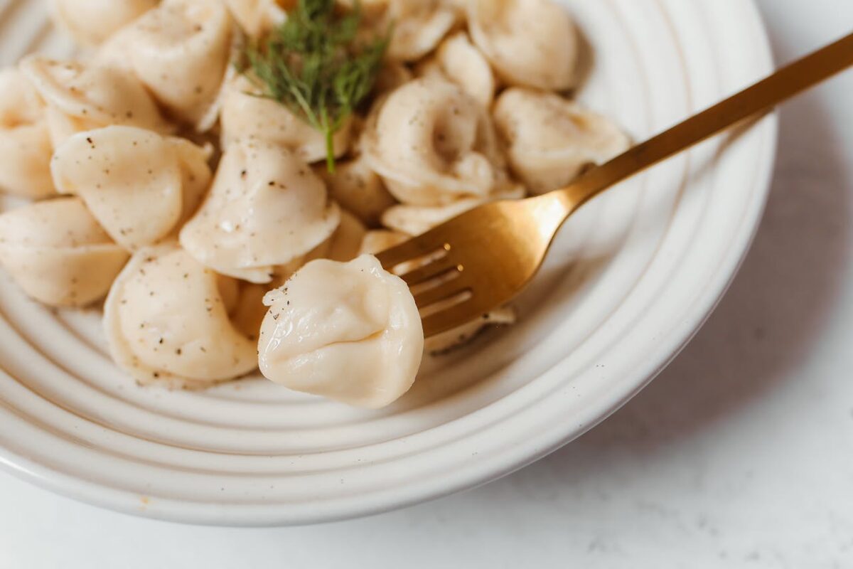 pexels photo 8601595 Delicious close-up of fresh dumplings with herbs on a white plate and fork.